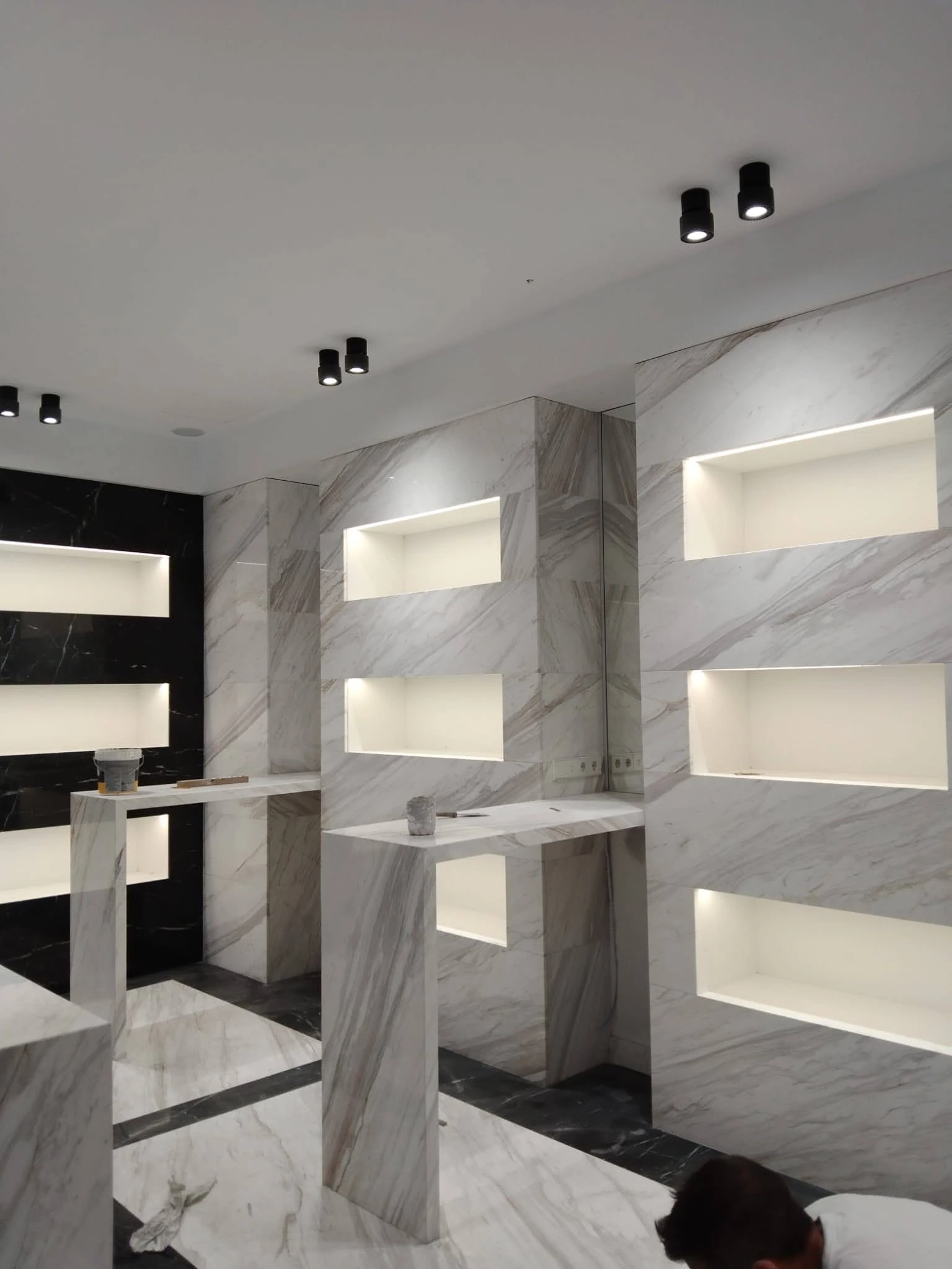 Showroom con paredes de mármol blanco, nichos iluminados y pedestales - Ropema Rubio