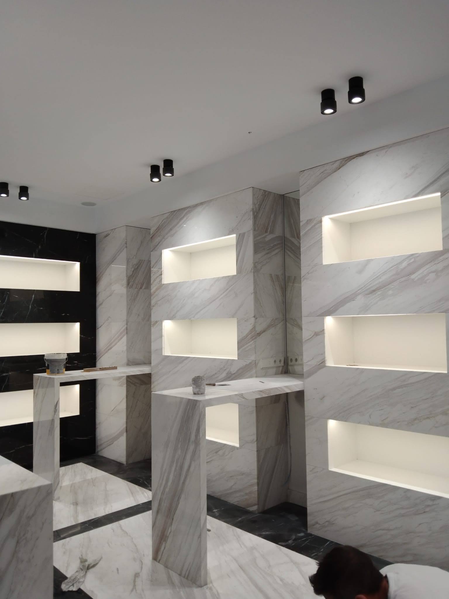 Showroom con paredes de mármol blanco y nichos iluminados - Ropema Rubio Madrid